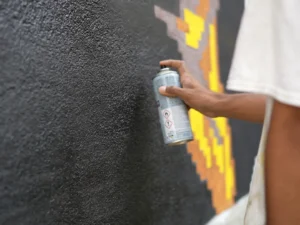 Man is painting the wall with graffiti spray